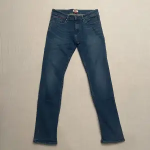 Säljer ett par snygga blå jeans från Tommy Jeans i modellen Slim Scanton. De har en slim passform och är i klassisk blå denim. Perfekta för både vardag och fest! 🕺w31 L34