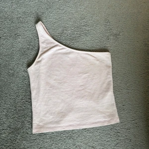 Ljusrosa oneshoulder topp från Gina Tricot - Säljer en snygg ljusrosa oneshoulder topp från Gina Tricot. Perfekt för sommardagar eller en utekväll. Toppen är ribbad och har en stilren design som passar till det mesta. Skön och lätt att bära!