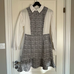 Svartvit rutig klänning med skjortdetalj - Snygg svartvit rutig klänning från bohoo med vit skjortdetalj och krage. Klänningen har långa ärmar och en volangkant nedtill. 