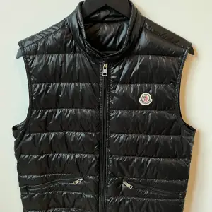 Svart Moncler väst. Storlek M. Kvitto och påse finns (se på andra bilden). Retail 7899. Skick 8/10, inga skador. Billigare går vid snabb och smidig affär.