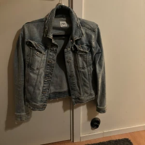 Jeansjacka från Zara - Säljer en snygg jeansjacka från Zara i storlek S. Den har en klassisk blå tvätt och är perfekt för vår och sommar. Jackan har knappar framtill och två bröstfickor med lock. Den är i bra skick och passar till det mesta i garderoben. Perfekt för en casual look! 💙