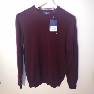 Vinröd ny lammullströja från GANT (lapparna kvar)  - Vinröd lammullströja från GANT. Ny oanvänd tröja med lapparna kvar. Storlek Small. Nypris 1200 kr. Unisex/herr