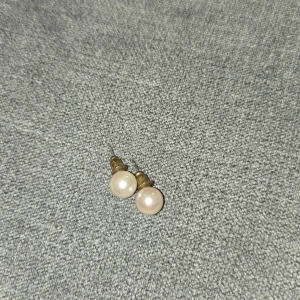 Pärlörhängen med gulddetaljer - Säljer ett par eleganta pärlörhängen med guldfärgade detaljer. Perfekta för både vardag och festliga tillfällen. De är i nyskick och ger en klassisk touch till vilken outfit som helst. Passar bra till både sommar och vinterstilar.
