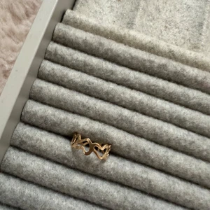 Guldfärgad ring med hjärtmönster - Säljer en superfin guldfärgad ring med ett unikt hjärtmönster. Perfekt för att ge en romantisk touch till din outfit. Ringen är i nyskick och passar de flesta storlekar. Perfekt för både vardag och fest! 💖