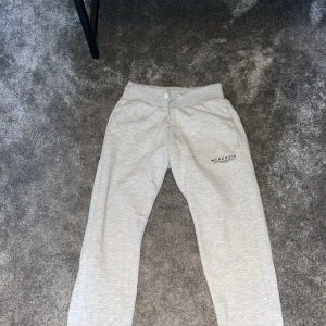 Grå mjukisbyxor från McKenzie - Säljer ett par grå mjukisbyxor från McKenzie i storlek herr M. De är superbekväma med en elastisk midja och snörning för perfekt passform. Perfekta för en chill dag hemma eller en snabb tur till affären. Byxorna har en enkel design med McKenzie-loggan på sidan.