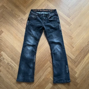 Rock Revival Jeans - Säljer dessa asfeta bootcut rocks i modellen ”Hank Boot”. Rock Revival jeans i svart/grå färg med bootcut passform är väldigt svårt att hitta, speciellt i så bra skick som dessa.   Hör av er vid ytterligare frågor!