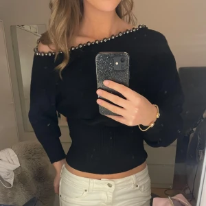 Svart tröja med pärlor - Så himla snygg tröja som ger en sån fin figur!💕 Man kan välja hur man vill ha den uppe vid axlarna! Har använt den Max 2 gånger så den är i toppen skick💕