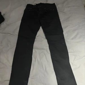 Svarta jeansbyxor - Snygga svarta jeansbyxor med en klassisk design. De har en smal passform och är perfekta för en stilren look. Byxorna har fickor både fram och bak samt en knapp- och dragkedjestängning.