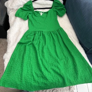 Grön klänning med puffärmar - Säljer en härlig grön klänning med puffiga kortärmar och en fyrkantig urringning. Klänningen har en texturerad yta och en luftig passform som ger en skön känsla. Perfekt för sommarens varma dagar! 💕🌸endast använd en gång