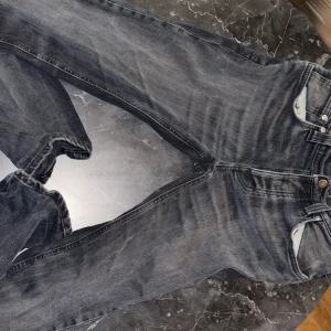 Mörkblå jeansbyxor - Säljer ett par mörkblå jeansbyxor från Nudie Jeans. De har en klassisk femficksdesign och en snygg tvättad look. Perfekta för en avslappnad stil. Midjan är normal och passformen är slim/straight. Dem har genomgått en reparation men detta är inget som syns när det är på. För fler bilder är det bara och skriva!