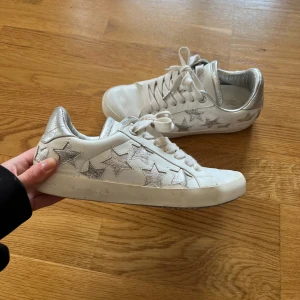 Zadig & Voltaire Sneakers - Storlek 37, 100% läder. Used effect design från början men använda och lite mer smutsiga samt veck på framsidan men är i bra skick. Vita med silvriga stjärnor.