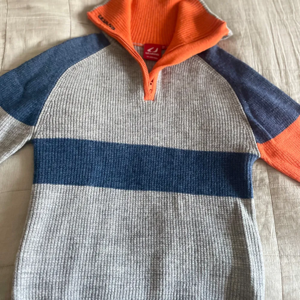Säljer en snygg randig tröja från Ulvang i ull. Tröjan har en dragkedja vid halsen och är i färgerna grå, blå och orange. Använd ett fåtal gånger. Nytt skick, men ingen prislapp.. Neuletakit & Villapaidat.