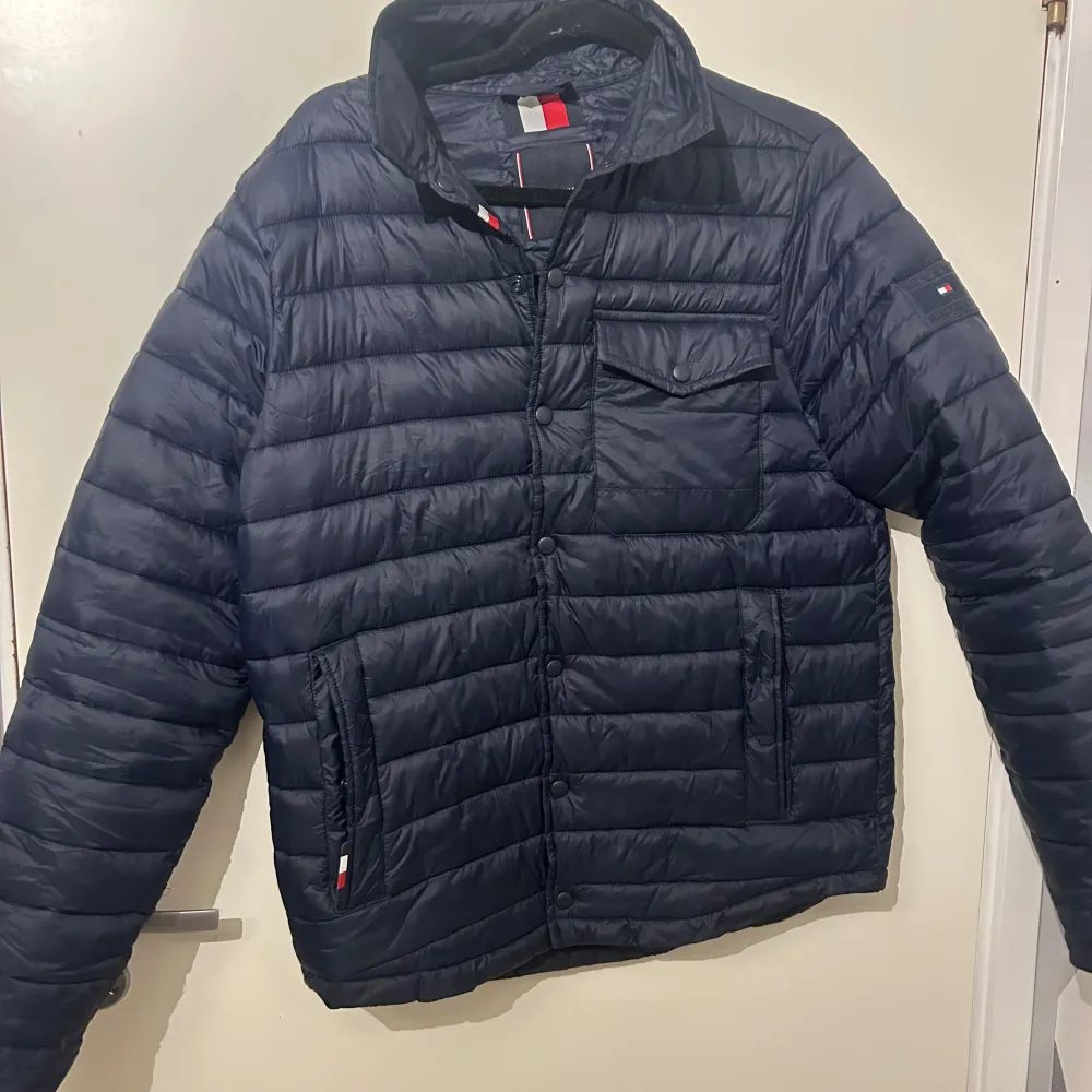 Mörkblå jacka från Tommy hilfiger. Kvitto följer med. Litet hål i höger ficka. Annars inga skador. Hör av er vid fler frågor. . Takit.