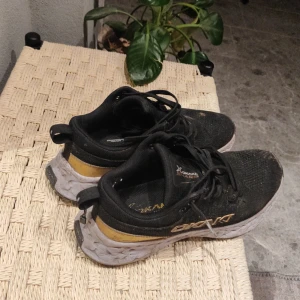 Svarta och gula sneakers från Okaki - Snygga svarta sneakers från Okaki med gula detaljer och vit sula. Skorna har snörning och en bekväm passform, perfekt för vardagsbruk. De har en modern design med märkets logga på sidan. Och är perfekt för träning och stillhet! De är nästan nya. Ny pris 600kr säljer dem för 200kr 
