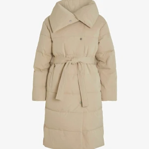 Beige dunjacka med bälte - Snygg beige dunjacka med knytbälte i midjan och stora knappar. Jackan har en hög krage och långa ärmar, perfekt för kyliga dagar. Den quiltade designen ger en stilren look. Jacka är från vila köpte nyligen men använd fåtal gånger bara. Helt ny och i bra skick. 