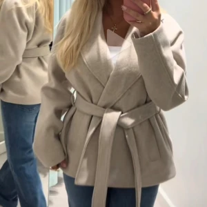 Beige kappa från Vero Moda - Säljer en snygg beige kappa med knytband i midjan från Vero Moda. Den heter ”VMFORTUNEAYA Short Jacket LCS” och är i storleken S, men den passar mig perfekt som XS. Originalpriset är 699 kr på hemsidan. (Inte mina bilder!!!)