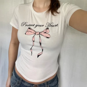 Coquette t-shirt - Vit söt t-shirt med rosetter på. Insydd i midjan så den är figursydd