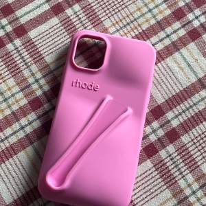Snyggt rosa mobilskal från Rhode med en unik design som inkluderar ett grepp på baksidan. Perfekt för att skydda din telefon och ge den en personlig touch. Skalet har en öppning för kameran och är lätt att sätta på och ta av. Köpt utomlands i en marknad i Spanien för 350 kr! För iPhone 11! Aldrig använd