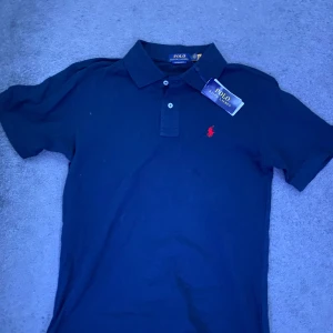 Blå pikétröja från Ralph Lauren - Säljer en stilren blå pikétröja från Ralph Lauren. Den är helt ny aldrig använd, skriv gärna så kan vi diskutera pris.