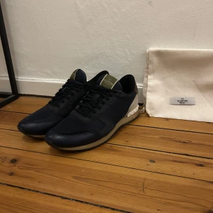 Valentino rockrunner  - Säljer ni mina Valentino rockrunner med ikoniska rockstud-detaljer på hälen. Det är storlek 42 men passar 43. Skorna har en kombination av mocka och skinn, vilket ger en lyxig känsla. De har en klassisk snörning och en diskret logga på plösen. Perfekta för en stilren look. Två dustbags medföljer. Hör av er vid frågor eller funderingar 