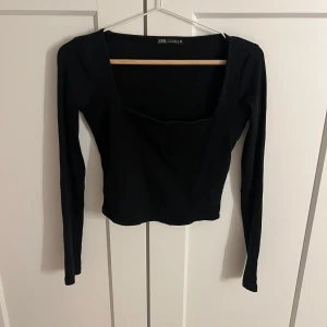 Svart långärmad topp från Zara - Snygg svart långärmad topp från Zara med fyrkantig urringning. Perfekt för en stilren look. Passar bra till både jeans och kjol.