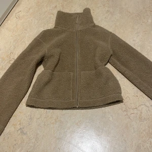Beige teddyjacka från H&M - Mysig beige teddyjacka från H&M med dragkedja framtill. Jackan har en hög krage och långa ärmar, perfekt för kyliga dagar. Den är tillverkad i ett mjukt och fluffigt material som håller dig varm och bekväm.Den är köpt på plick och har inga defekter. Fastpris 235kr☺️