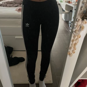 Svarta leggings från Adidas - Snygga svarta leggings från Adidas med de klassiska tre vita rände. Adidas-loggan på framsidan. Är i st xs och nytt skick.