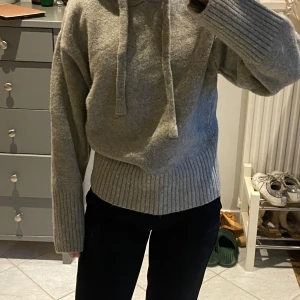 Grå stickad hoodie från Zara - Säljer denna jättemysiga sköna stickade tröjan med livs från Zara. Den passar verkligen att ha till jeans, kostymbyxor eller en kjol men också att ha hemma som myströja. Den är aldrig använd så den är inprickat som helt ny.