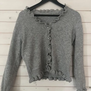 Grå kofta med volangdetaljer - Söt kofta. Använd få gånger, väldigt bra skick.