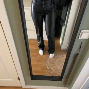 Svarta skinnbyxor - Snygga svarta skinnbyxor. Byxorna har en stilren design med dragkedja och knappar framtill. Perfekta för en trendig look. Använda max 2 gånger så i mycket fint skick.