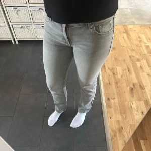 Grå jeans från Pull&Bear - Snygga grå jeans från Pull&Bear med en klassisk femficksdesign. De har en rak passform och är perfekta för en avslappnad stil. Jeansen har en knappgylf och är tillverkade i ett bekvämt denimtyg.