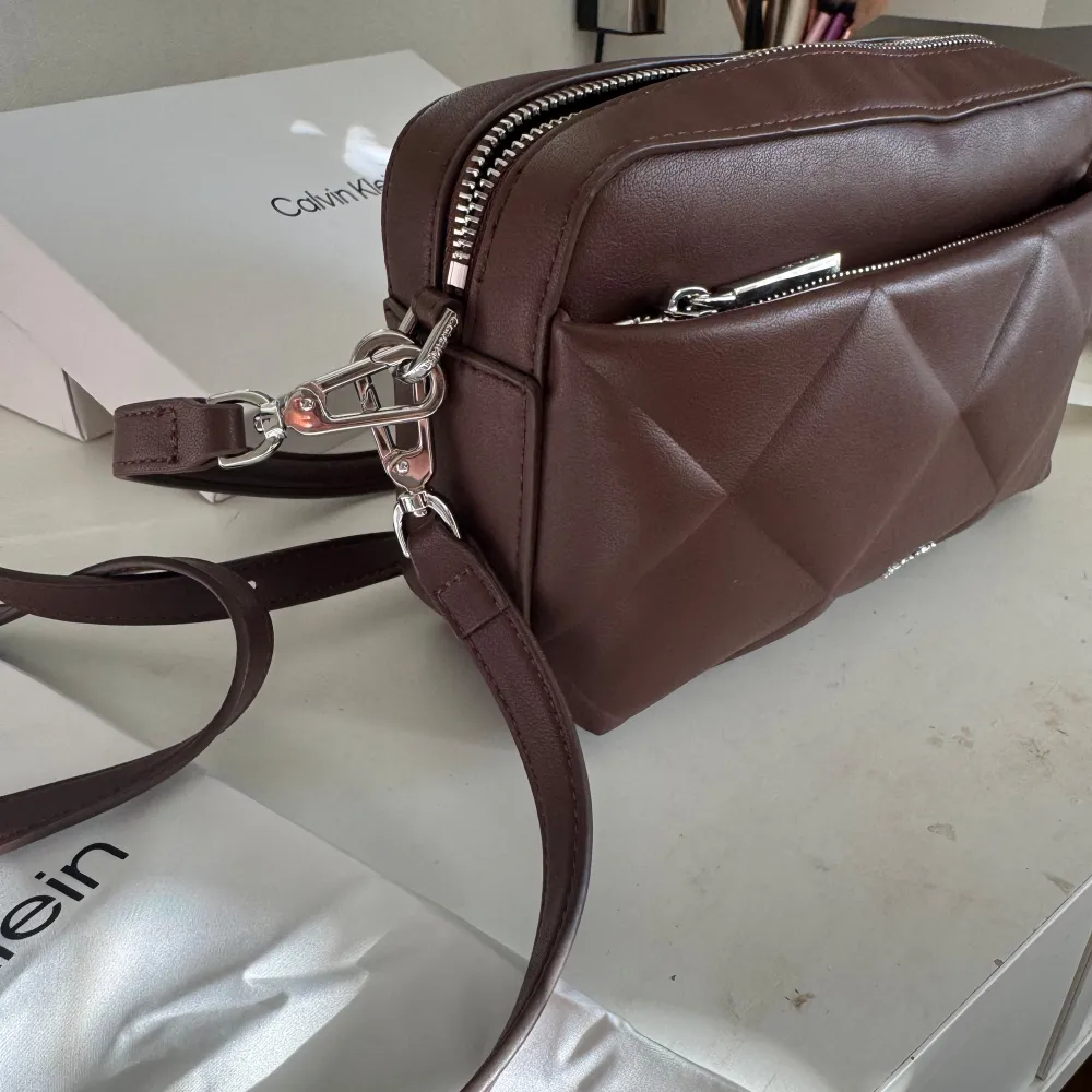 Brun Calvin Klein väska. Aldrig använd, prislappen är kvar. Kommer med både långa och korta band så fungerar som både handväska och axelväska.. Laukut & Käsilaukut.