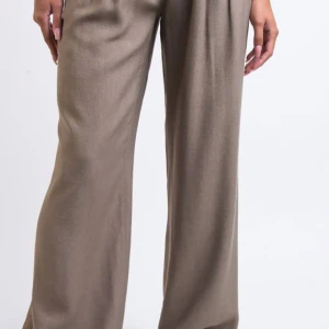 Beige vida byxor leoa  - Snygga beige byxor med en loose passform och hög midja. Perfekta för en stilren look. Materialet ger en elegant känsla och de vida benen ger en modern touch.