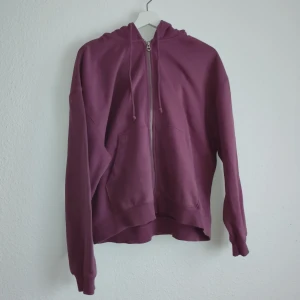Lila hoodie från Weekday - Säljer en snygg lila hoodie från Weekday i storlek S. Den har en dragkedja framtill och en praktisk huva med dragsko. Perfekt för en avslappnad stil.