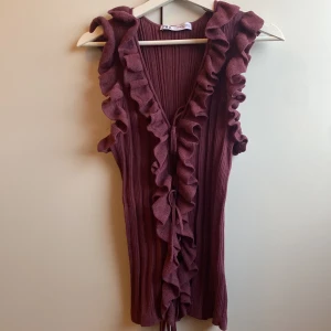 Vinröd blus från Zara - Säljer en snygg vinröd blus från Zara med volangdetaljer längs kanterna. Den är helt ny och i perfekt skick då den aldrig har varigt använd.