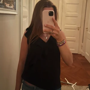 Svart ärmlös topp - Snygg svart ärmlös topp med v-ringning. Perfekt för en stilren look. Passar bra till både jeans och kjol.