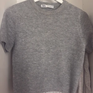 Slutsåld Zara topp! - Mysig grå stickad tröja från Zara med korta ärmar. Perfekt för lager-på-lager under kyligare dagar. Enkel och stilren design som passar till det mesta.