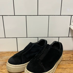 Svarta sneakers från Eytys - Snygga svarta sneakers från Eytys i mocka med en stilren design. Skorna har en vit sula och en lila detalj baktill. Stl 39. Väldigt sparsamt använda.