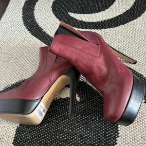 Vinröda klackade boots - Snygga vinröda boots med hög klack och platåsula. Tillverkade i skinn med en elegant spetsig tå. Perfekta för att lyfta vilken outfit som helst.