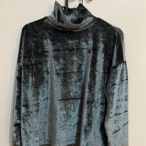 Grå sammetströja från Champion - Säljer en stilren grå sammetströja från Champion. Tröjan har en hög krage och långa ärmar, perfekt för en avslappnad look. Den mjuka sammeten ger en lyxig känsla. Passar perfekt för kyligare dagar.