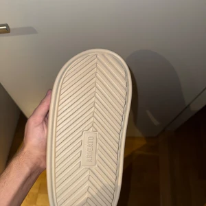 Beige sandaler från Axel Arigato - Snygga och minimalistiska beige sandaler från Axel Arigato. Perfekta för en avslappnad stil med en modern touch. Sandalerna har en stilren design med öppen tå och är tillverkade i syntetmaterial.  Ingen låda bara dust bag 