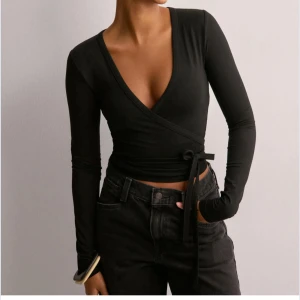 Svart omlopp topp - Helt oanvänd!!! Snygg svart balett topp från Nelly med långa ärmar och knytning i midjan. Toppen har en v-ringad design. Tröjan fick jag i julklapp men tyvärr var den för liten därav är den helt oanvänd💞🩷