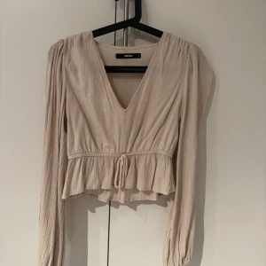 Beige blus från Bik Bok -  beige blus från Bik Bok med v-ringning och långa ärmar. storlek XS