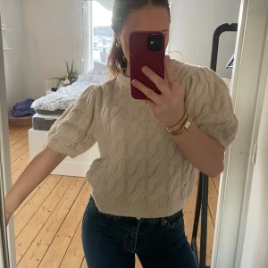 Beige stickad tröja/t-shirt/topp - Säljer en mysig beige stickad tröja med korta ärmar och ett klassiskt flätmönster. Perfekt för en stilren och bekväm look. Passar bra till jeans eller kjol.❣️❣️