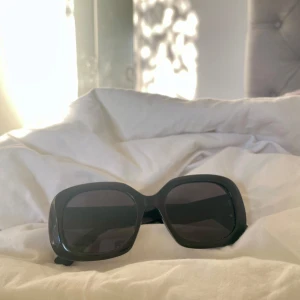Svarta solglasögon med breda bågar - Snygga svarta solglasögon med breda bågar och fyrkantig form. Perfekta för en stilren look och skyddar mot solen med sina mörka glas.