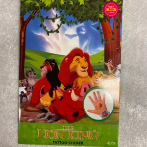 The Lion King Tattoo Klistermärken med Presentförpackning  - Ett set med över 100 tatueringar är tklistermärken från The Lion King. Innehåller fyra ark med olika motiv av karaktärer som Simba, Timon och Pumbaa. Perfekt för att dekorera eller använda som tillfälliga tatueringar. 3 år + 
