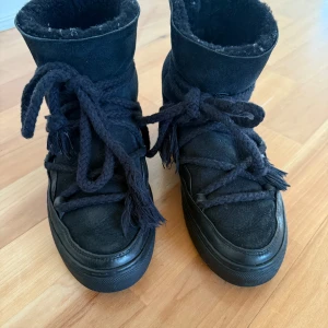 Svarta boots från Inuikii - Snygga svarta boots från Inuikii i mocka och skinn. De har en hög design med snörning och en varm insida,. Stl 37. Inköpta 2023