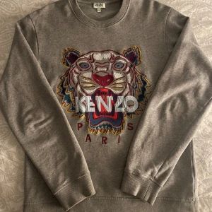 Grå sweatshirt från Kenzo - Helt ny grå sweatshirt från Kenzo säljer den för gillade inte färgerna (fick den i present), bra passform. Kollat upp priser och den går för cirka 2500-2800 och jag säljer den för 1200, pris kan diskuteras.