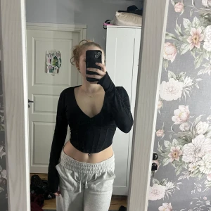Svart långärmad urringad top - Snygg svart top med långa ärmar och djup v-ringning. Perfekt för en trendig look.🥰