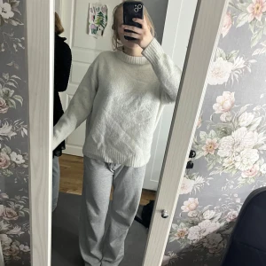 Vit stickad tröja - Mysig vit stickad tröja med polokrage. Perfekt för kyliga dagar med sin bekväma passform och långa ärmar. En klassisk och stilren design som passar till det mesta.